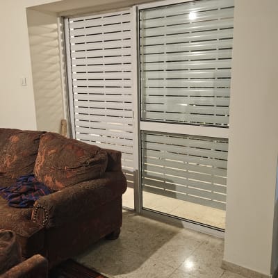 תריסים לבנים סגורים על חלון זכוכית גדול