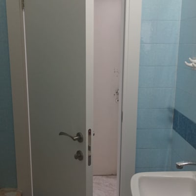 דלת פתוחה בחדר אמבטיה עם כיור וקיר כחול