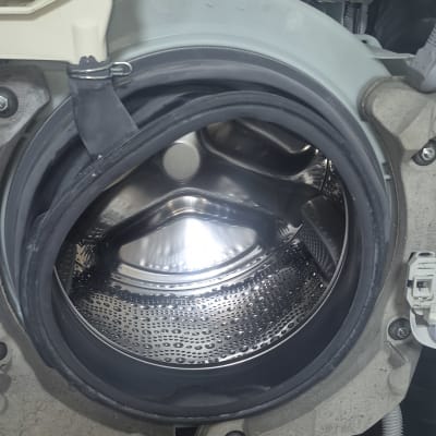 תוף מכונת כביסה פתוח עם חלקים פנימיים גלויים