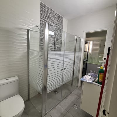 מקלחון זכוכית עם דלתות, שירותים וכיור בחדר אמבטיה מודרני