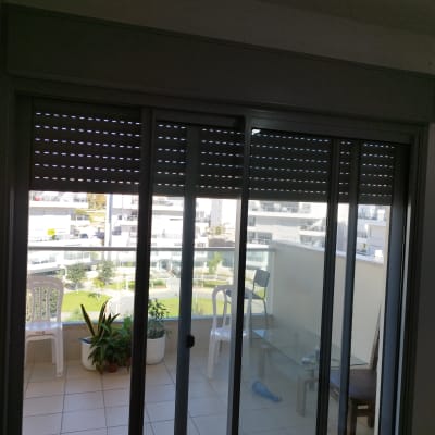 תריסים סגורים למחצה על חלון זכוכית במרפסת