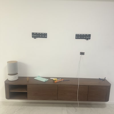 מתקן טלוויזיה על קיר עם כלים על שידה