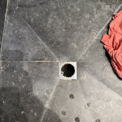 רצפת אריחים עם חור ניקוז ומטלית אדומה