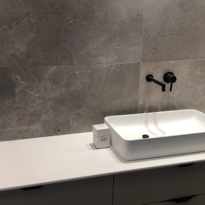 קיר שיש אפור עם כיור לבן וברז שחור