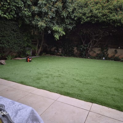 אדם עובד בגינה עם מפוח על דשא ירוק