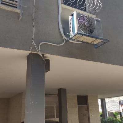 יחידת מיזוג אוויר מותקנת על קיר חיצוני של בניין.