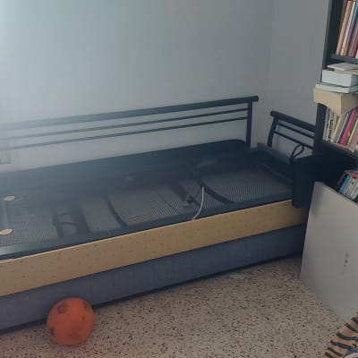 חדר עם מיטה, מדף ספרים וכדור כתום על הרצפה