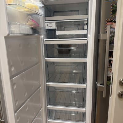 מקרר פתוח עם מדפים ריקים ומעט פריטים בדלת