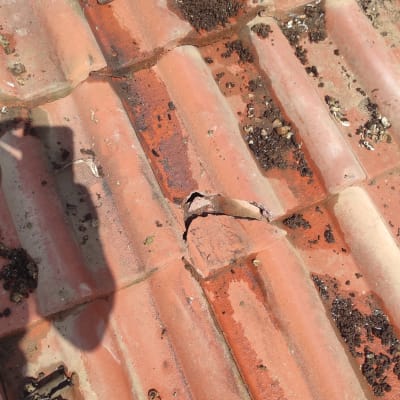 רעפים שבורים על גג עם מפתח צינורות