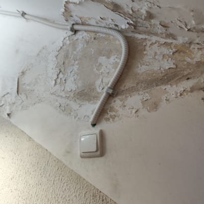 מתג חשמל וצינור פלסטיק על קיר מתקלף