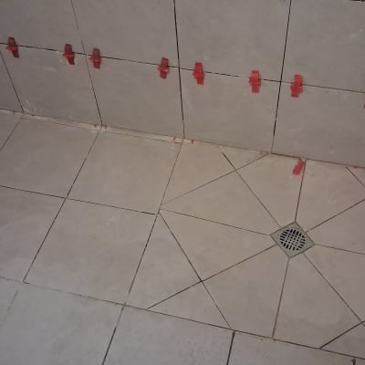 אריחים מותקנים עם תפסנים אדומים בחדר אמבטיה