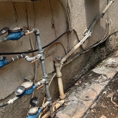 צינורות מים ומדי מים מחוברים לקיר חיצוני