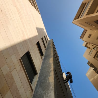 אדם עובד בגובה על בניין עם חבלים