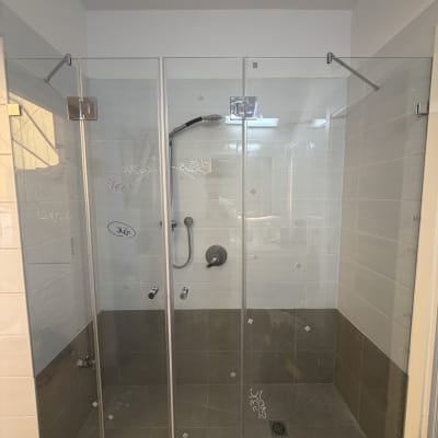 מקלחון זכוכית בחדר אמבטיה עם אריחים אפורים