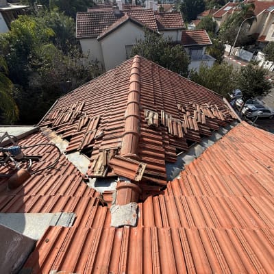 רעפים שבורים על גג רעפים אדום עם נזק