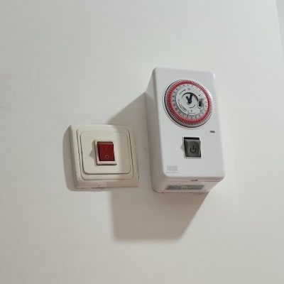 מתג חשמלי ושעון טיימר על קיר לבן