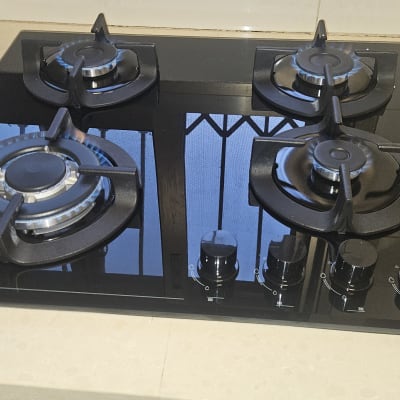 כיריים גז שחורות עם ארבעה מבערים וכפתורי שליטה