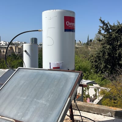 דוד שמש עם קולטים על גג תחת שמיים כחולים