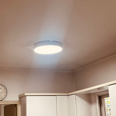 מנורה עגולה מותקנת בתקרה מעל ארונות מטבח לבנים