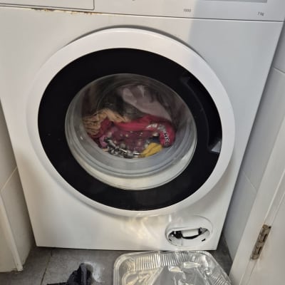 מכונת כביסה עם מגש אלומיניום וגרב על הרצפה
