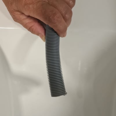 יד מחזיקה צינור גמיש אפור מעל כיור