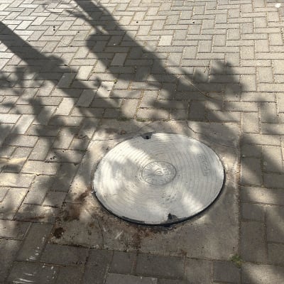 מכסה ביוב עגול על מדרכה מרוצפת