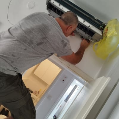 אדם מתקן מזגן תלוי על קיר