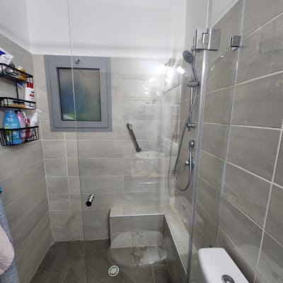 מקלחת עם דלת זכוכית, ראש מקלחת ומדף מוצרים