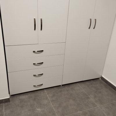 ארון לבן עם ידיות מתכת על רצפת אריחים אפורה