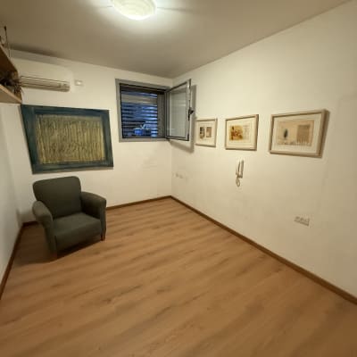 חדר עם רצפת פרקט, כורסה ותמונות על הקיר