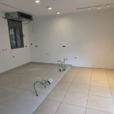 חלל דירה בשלבי שיפוץ ובנייה עם צנרת גלויה וריצוף