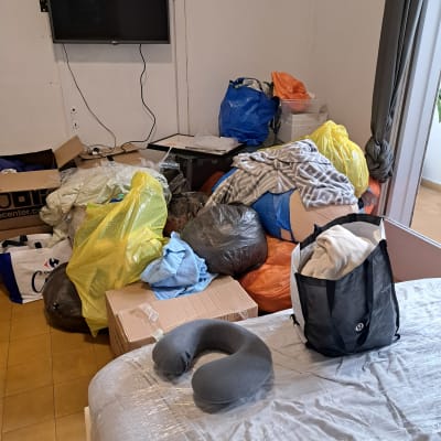 חדר עם שקיות בגדים, קופסאות וציוד לא מסודר