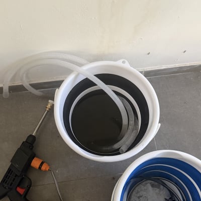 דלי עם צינור וכלי עבודה על הרצפה