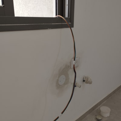 חוטי חשמל יוצאים מקיר ליד שקע חשמל