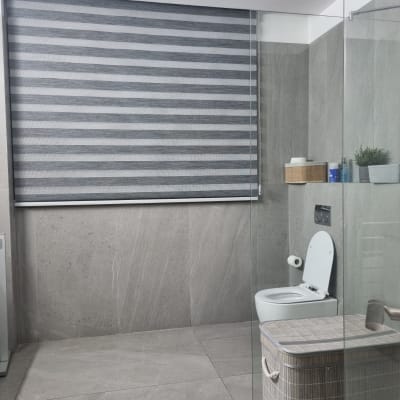 וילון גלילה אפור בחדר אמבטיה מודרני עם שירותים וסל כביסה.