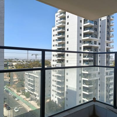 מרפסת עם מעקה זכוכית ונוף לבניינים גבוהים