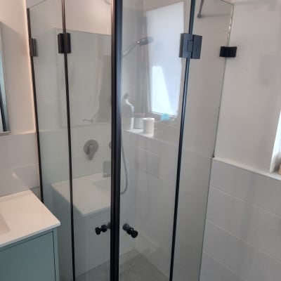 מקלחון זכוכית עם ראש מקלחת ומדף מוצרים