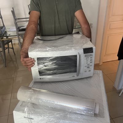 אדם נושא מיקרוגל עטוף בניילון