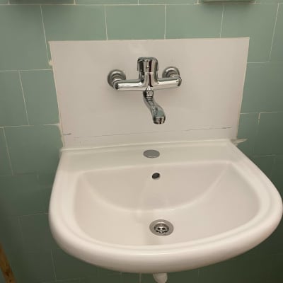 כיור עם ברז כרום מותקן על קיר אריחים ירוקים