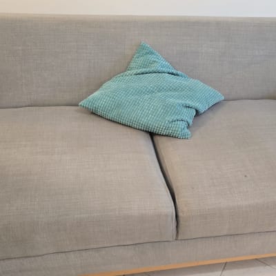 ספה אפורה עם כרית טורקיז על המושב