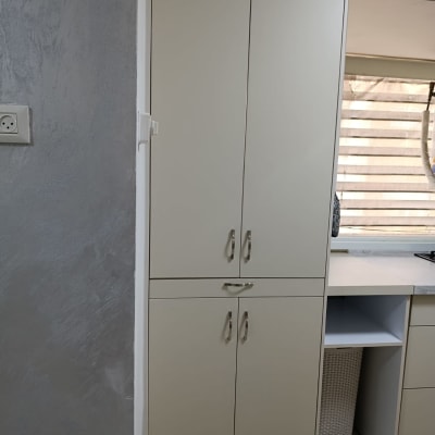 ארונות מטבח עם ידיות מתכת וקיר אפור