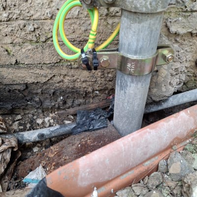 חוטי חשמל ירוקים וצהובים מחוברים לצינור מתכת