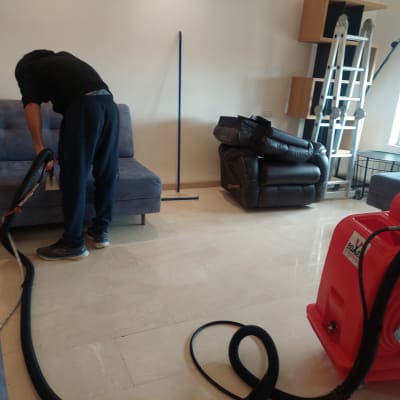 אדם מנקה ספה עם שואב אבק תעשייתי אדום