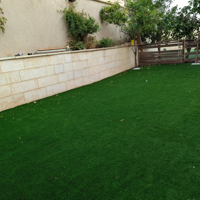 דשא סינתטי עם עצים וגדר עץ בגינה