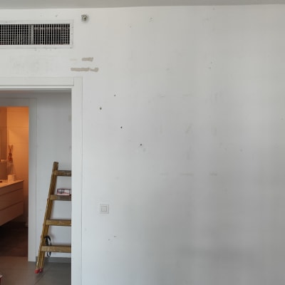 סולם עץ ליד קיר לבן עם סימני צבע