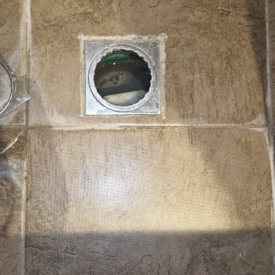 קופסת ניקוז רצפתית פתוחה ברצפת אריחים במהלך עבודת אינסטלציה