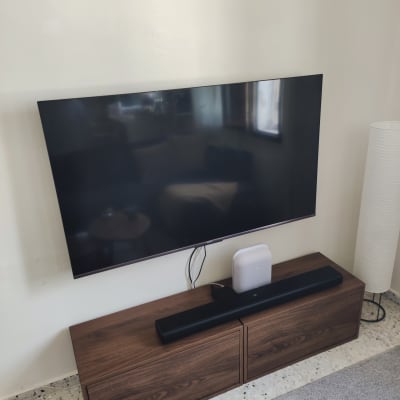 טלוויזיה תלויה על קיר עם רמקול ומזנון עץ