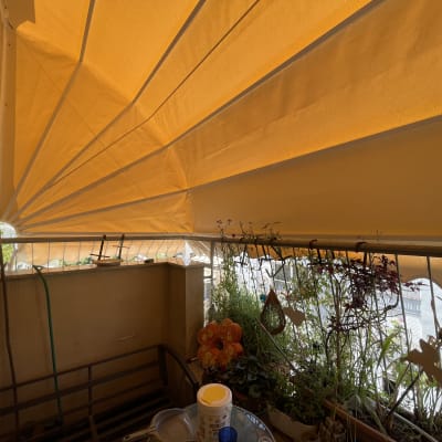 סוכך כתום נפרש מעל מרפסת עם צמחים