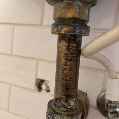 צינור מתכת עם חלודה וחיבורים מתחת לכיור