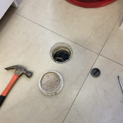 פתח ניקוז פתוח עם פטיש ומכסה על הרצפה